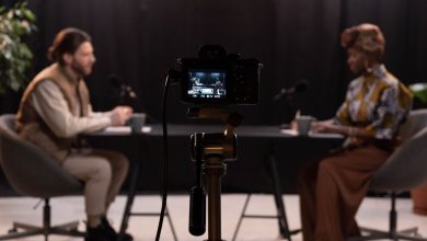 Dois apresentadores gravam um podcast em um estúdio equipado com microfones e outros recursos profissionais.