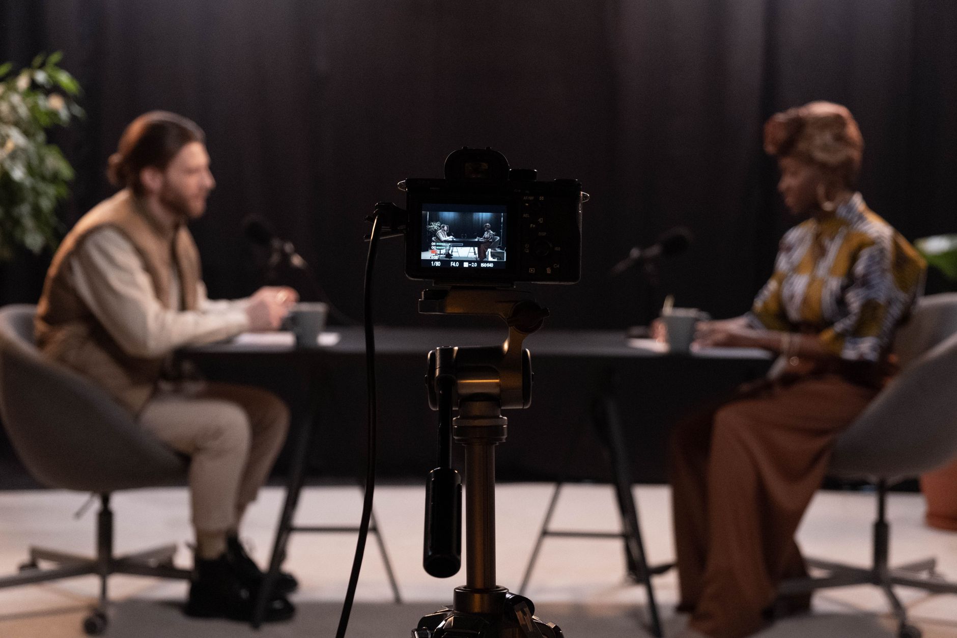Dois apresentadores gravam um podcast em um estúdio equipado com microfones e outros recursos profissionais.