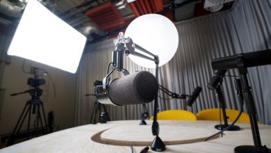 Estúdio moderno de podcast com microfones, cadeiras e equipamentos de iluminação.